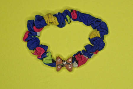one colored fabric bracelet with a brown plastic bow tie lies on a yellow table