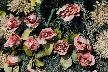 texture of red artificial buds of rose flowers with green leaves in a wreath