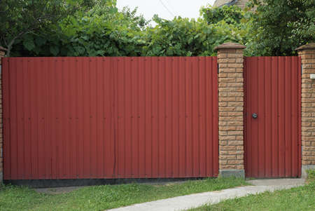 big red metal gate and closed door on a rural street