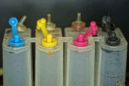 row of white plastic bottles with colored caps for printer inks