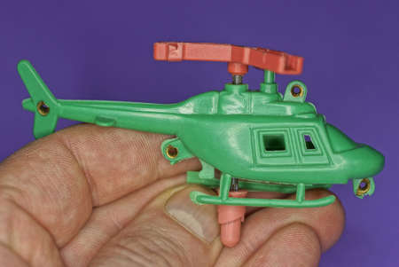 one green plastic toy helicopter in hand on a purple backgroundの写真素材