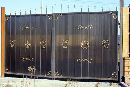 gray brown metal gate with gold iron wrought iron pattern outdoors
