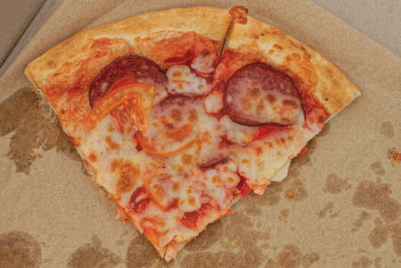 food and pieces of red pizza carbonara in a gray paper carton box
