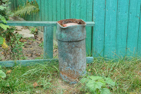 one old green rust metal gas cylinder dug into the ground in the grass near the fence outside