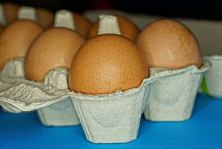 part on a gray paper packaging box with brown eggs on blue table