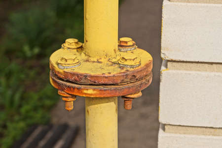part of the yellow iron gas pipe on the white brick wall of the building in the street
