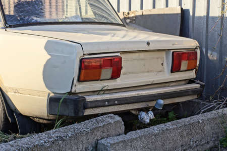 part of an old brown passenger car with a black bumper and red headlights on the street