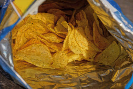 open plastic package with a bunch of dry yellow chipsの写真素材