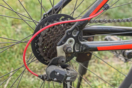 part of a black red sports bike with a wheel and sprockets with an iron chain on the frame on the...