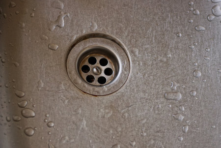 part of a gray metal wet sink with a round spout in the kitchenの写真素材