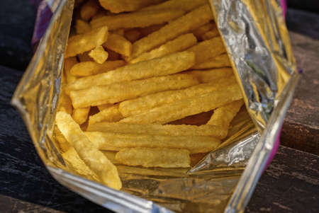 open gray plastic package with a pile of dry yellow potatoes