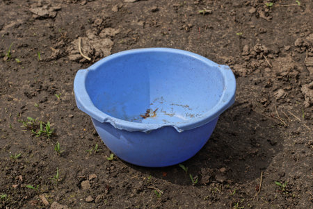 one old empty blue plastic broken bowl stands on the gray ground in the streetの写真素材