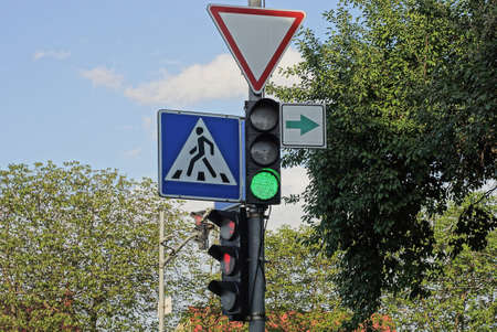 a pole with road signs and traffic lights on the street against the background of a blue sky and...