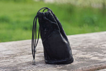 one small black leather bag a purse stands on a wooden gray table