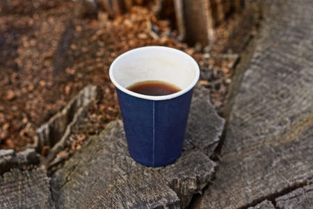 one blue paper cup with brown coffee stands on a gray wooden table in the streetの写真素材