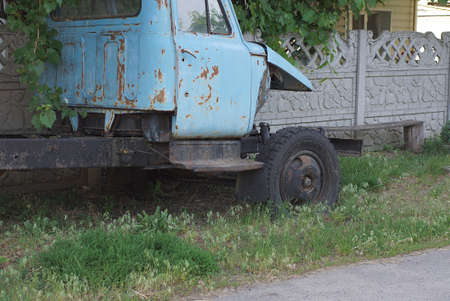 one old disassembled truck with a blue cab stands on the street in green grassの写真素材