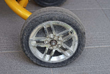 one black white plastic wheel on a trolley stands on a gray pavement in the streetの写真素材