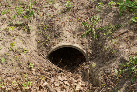 one large iron sewer pipe in the gray earth and green grass on the street