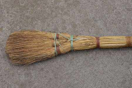 one old brown wooden broom lies on gray asphalt in the street