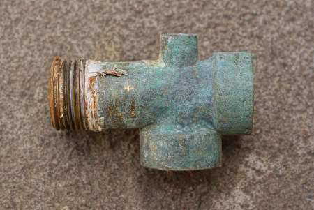 one old green brass nut plumbing adapter lies on a gray table