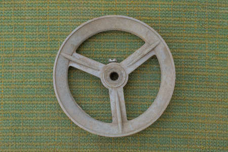 one old gray plastic wheel from a wheelbarrow lies on a green tablecloth