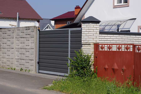 one large black closed metal gate on a white brick wall of the fence on the street