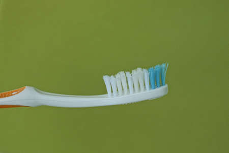 one white blue plastic toothbrush on a green backgroundの写真素材