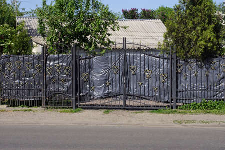 black metal gate and a door made of iron bars in a wrought iron pattern and part of the fence wall...