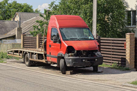 an old disassembled truck with a red cab stands on the street near a gray road near a brown wooden fence wallの写真素材