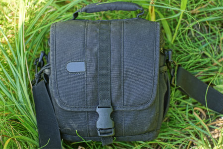 one dirty black closed bag a wardrobe trunk made of fabric lies on the green grass in natureの写真素材