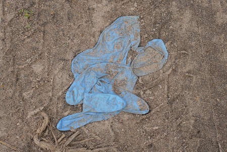 one old blue crumpled rubber glove lies in the gray ground on the street