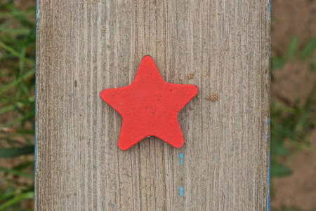 one red wooden toy star lies on a gray sandbox board in a playground outdoors