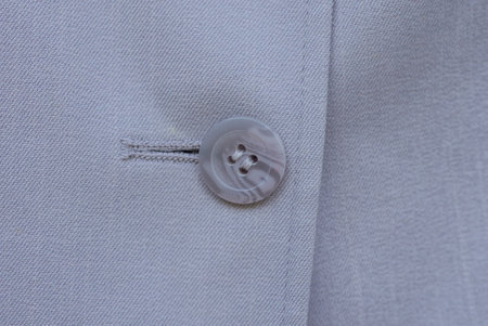 part of clothing made of brown fabric and one big gray plastic button