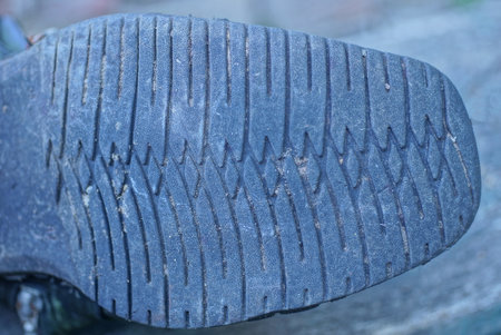 part of the boot with a rubber dirty old sole with a black pattern on a gray backgroundの写真素材