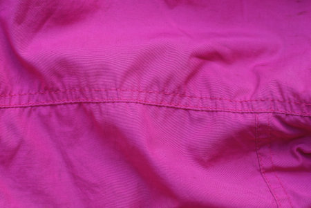 red fabric texture of pink crumpled clothes with a seam