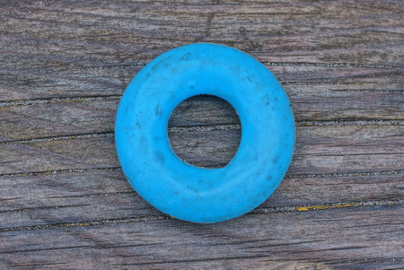 one blue round plastic toy ring lies on a gray wooden board in the street