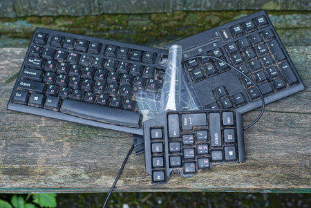 pieces of a broken broken plastic black computer keyboard lie on a gray wooden table in the streetの写真素材