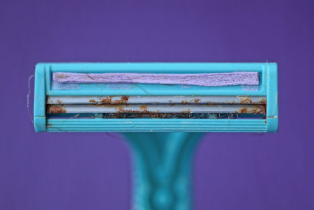 one barn blue plastic razor with rusty blades on a lilac backgroundの写真素材