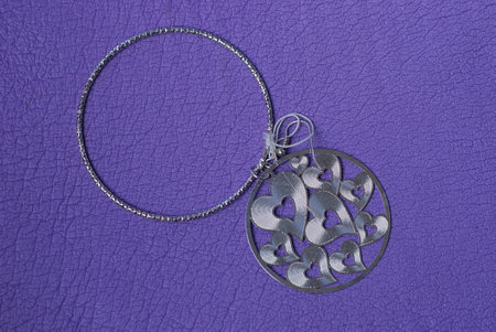 a jewel of two gray silver rings earrings with small hearts lies on a purple table