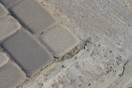 corner of an alley made of gray paving slabs on dirty concrete in the streetの写真素材