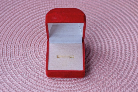 one small open red white ring box stands on a pink tableの写真素材