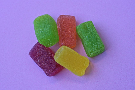 food from a set of colored marmalade candies lie on a pink tableの写真素材