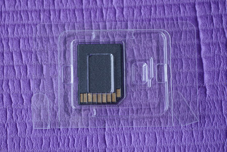 one small black removable storage device in a transparent plastic package lies on a purple table