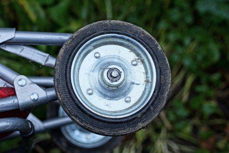 small dirty gray black metal and plastic wheel on a trolley outdoors on a green background