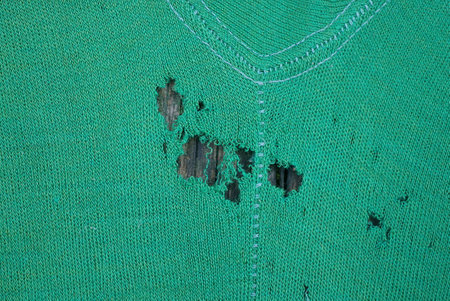 green fabric texture of torn clothes with a gray holeの写真素材