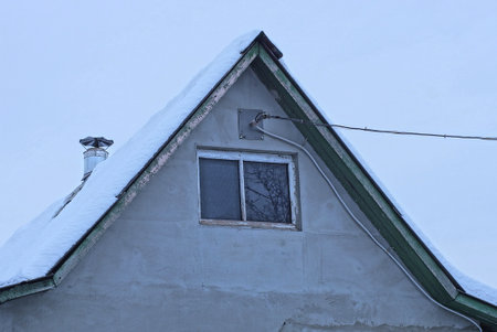 one gray concrete attic of an old private rural house with a small window with white snow on the...
