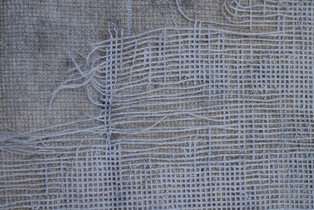 fabric texture of white torn threads on a gray old piece of matter