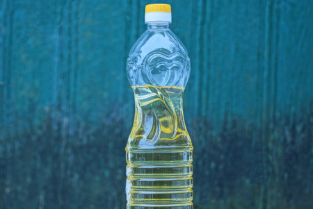 one plastic bottle full of yellow sunflower oil against a green wall