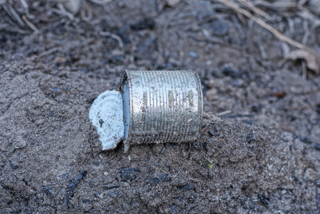 garbage from one white dirty aluminum tin can lies on the gray ground on the streetの写真素材