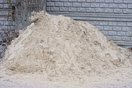 big white pile of sand outside near the gray concrete wall of the fenceの写真素材